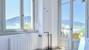 A room with a view of mountains, a radiator, a black metal stand, and a white table.