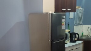Een kleine keuken met een koelkast, een koffiezetapparaat en een spoelbakje.