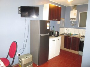 A compact kitchen with a refrigerator, microwave, kettle, and stove. - C3 Furnished Cabin Close to downtown Puerto Montt (Coyhaique)