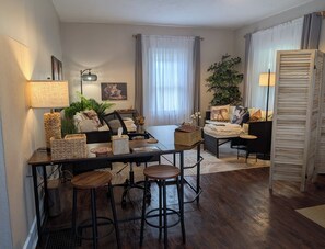 Una sala de estar acogedora con un sofá, una mesa de centro, una mesa de comedor y una zona de bar.