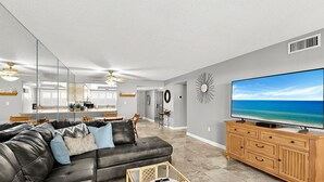 Una sala moderna con un sofá de cuero, un televisor y un mueble de madera.