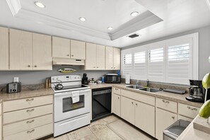 A modern kitchen with white cabinetry, a built-in oven, a dishwasher, and a microwave. - Ground-Floor Condo Steps from Beach (Siesta Key)