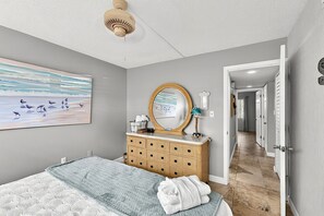 Una camera da letto con un letto, una cassettiera, uno specchio e opere d'arte alle pareti.