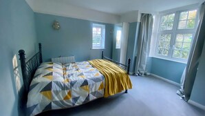 A bedroom with a bed, a window, and a door.