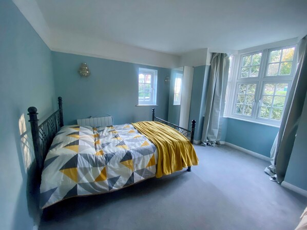 A bedroom with a bed, a window, and a door.