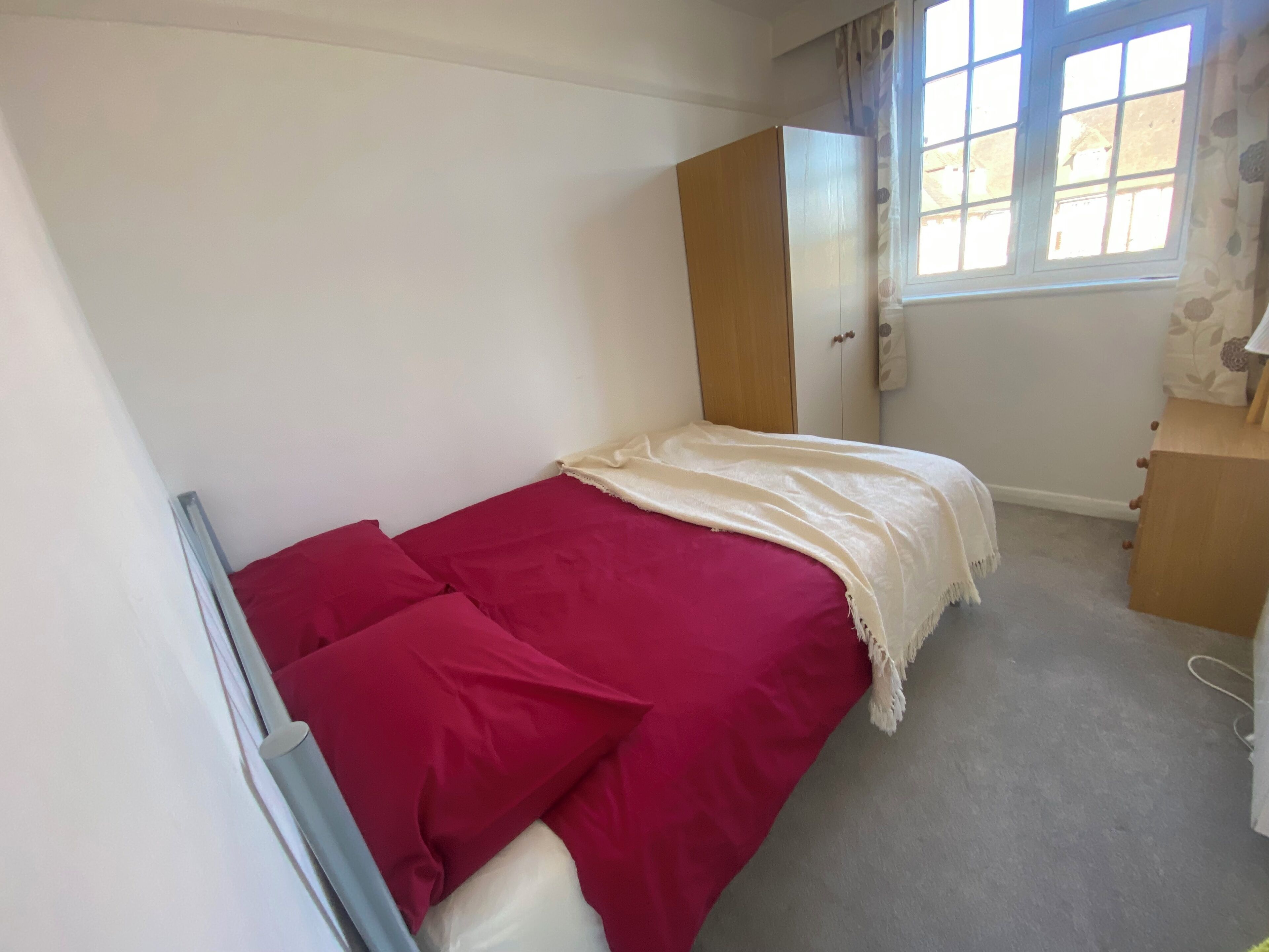 A bedroom with a bed, a wardrobe, and a window.