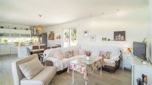 Ein modernes Wohnzimmer mit einer Couch, einem Glastisch und einem Fernseher.