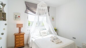 Ein Schlafzimmer mit einem Bett, einem Nachttisch, einer Lampe, einem Fenster mit Blick und einem Wandbild.