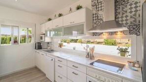 Eine moderne Küche mit weißen Schränken, einem eingebauten Backofen und einem Fenster mit Blick auf Grünflächen.