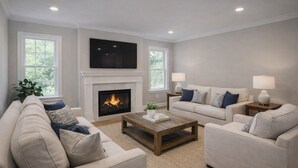 Ein Wohnzimmer mit Kamin, zwei Sofas, einem Couchtisch und einem Fernseher über dem Kamin.