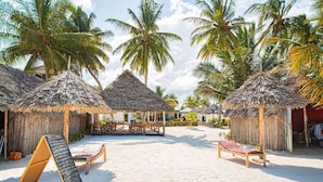 A beachside resort with thatched-roof huts, a sandy beach, and palm trees. - Zanzibar holiday villa (Zanzibar)