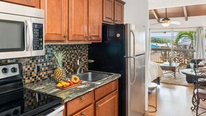 Una cocina con armarios de madera, microondas, estufa y refrigerador.