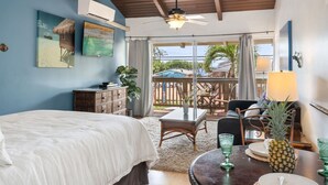 Un dormitorio con cama, escritorio, silla, mesa con piña y balcón con vistas.