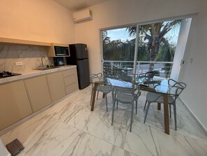 A modern kitchen with a dining area, large sliding glass doors to a balcony, and a view of palm trees. - Charming 2-bedroom apartment with AC in San Miguel de Cozumel (San Miguel de Cozumel)