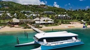 Ett flytande hotell med modern design, en brygga och en strand i bakgrunden.
