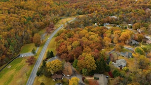 Vue aérienne d’un quartier résidentiel avec des maisons, des routes et un paysage vallonné.