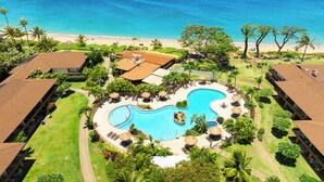 Ein Resort mit einem zentralen Schwimmbad, Zugang zum Strand und tropischer Bepflanzung.