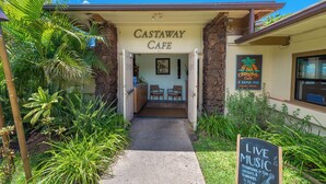 Ein Café Eingang mit einem Schild mit der Aufschrift 'CASTAWAY CAFE', einem Kreideboard, das Live-Musik bewirbt, und einem einladenden Schild.