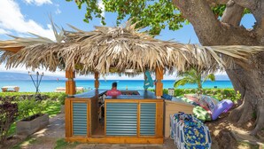 Eine Strandbar mit Reetdach, einer Theke und Liegestühlen.