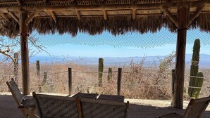 A covered seating area with a view of a desert landscape, including cacti and distant mountains.