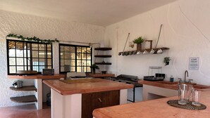 A kitchen with a central island, a stove, a sink, and a window with a view.