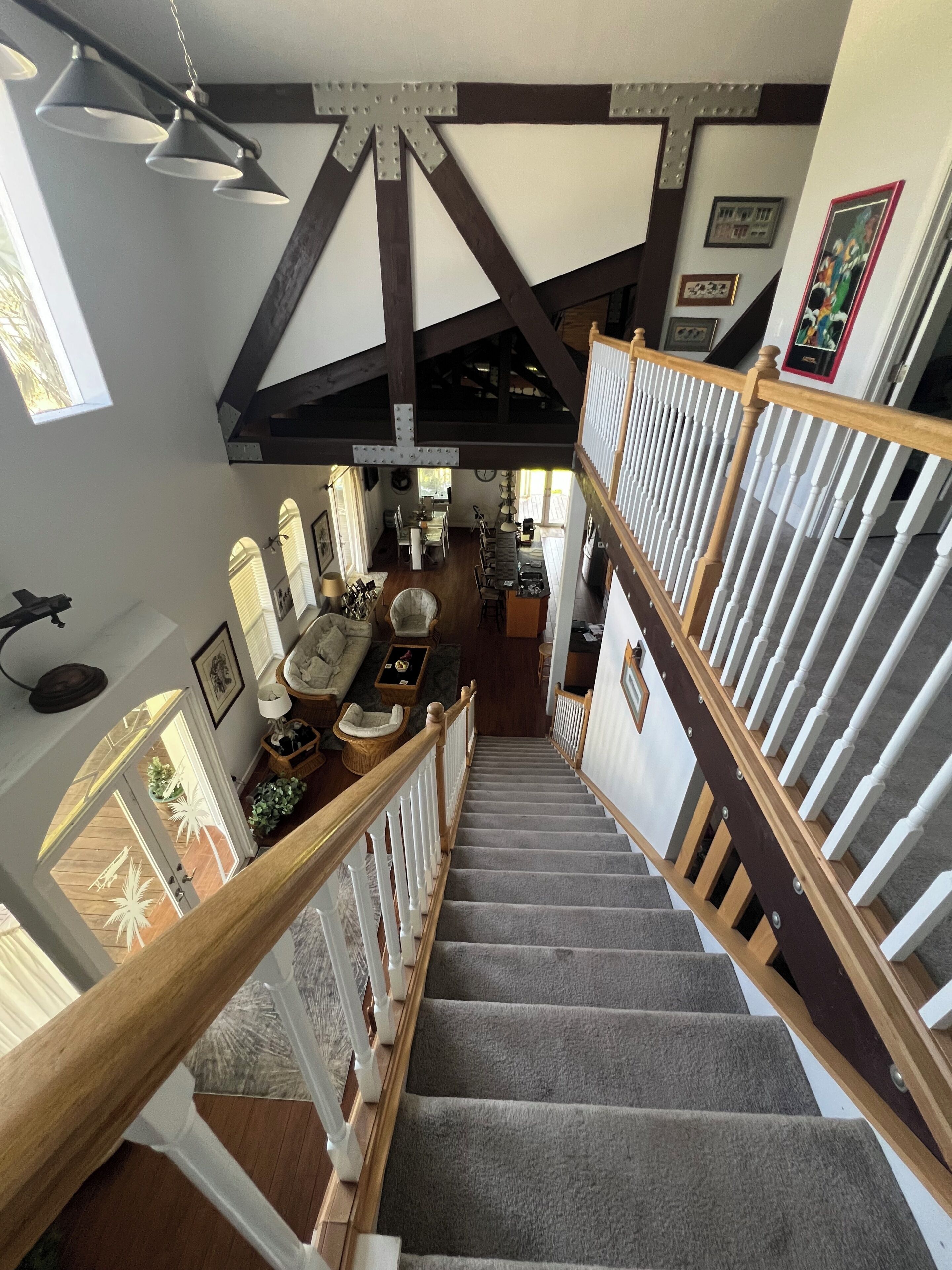 A staircase with wooden railings and carpeted steps leading to a second-floor area with a dining table and chairs.