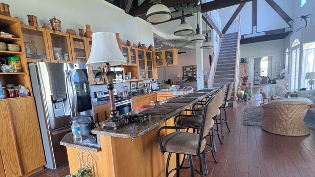 Un'ampia cucina con mobili in legno, un'isola centrale con sgabelli da bar e un'ampia finestra che offre luce naturale.