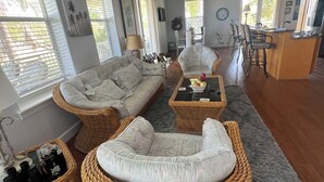 Un'ampia zona giorno con mobili in vimini, un tavolo da pranzo e una cucina con un bancone.