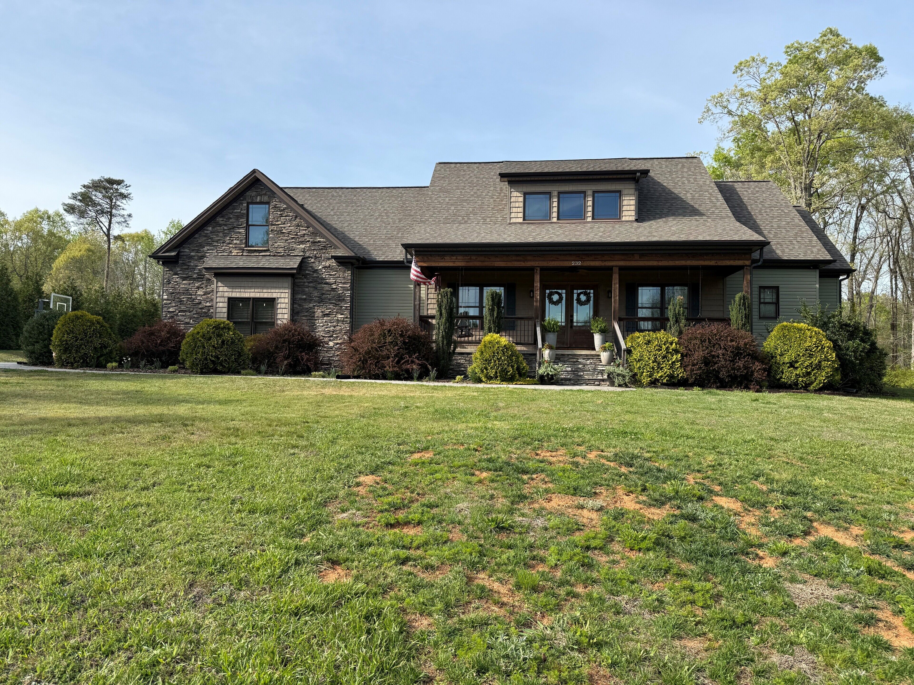 A two-story house with a stone facade, a front porch, and a well-maintained lawn.