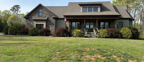 A two-story house with a stone facade, a front porch, and a well-maintained lawn.