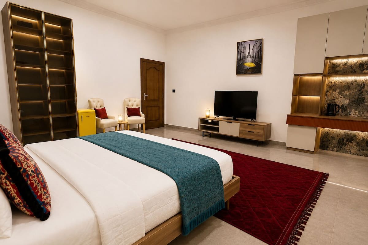 A modern bedroom with a bed, a TV, a wardrobe, and a red carpet.