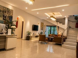 Un vestíbulo amplio con mostrador de recepción, zona de estar, escalera y obras de arte en las paredes.