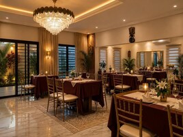 Un comedor formal con mesas dispuestas para el servicio, una araña y un amplio ventanal con cortinas.