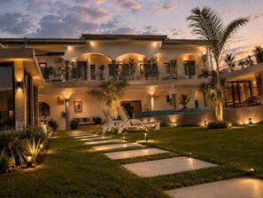 A multi-story building with a pool, outdoor seating, and a well-lit garden area.
