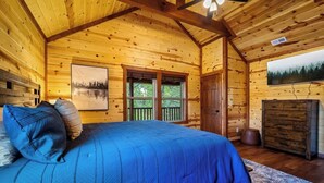 Une chambre dans une cabane en rondins, avec un lit, une fenêtre et un tableau accroché au mur.