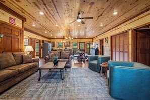 A log cabin interior with a living room, dining area, kitchen, and a fire riser room sign.