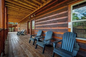 A log cabin with a wooden deck and Adirondack chairs.