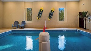 Une piscine avec deux chaises et deux planches de surf accrochées au mur.