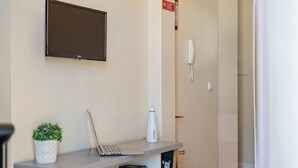 En receptionsdisk med en bärbar dator, en krukväxt, en vattenflaska och en telefon.