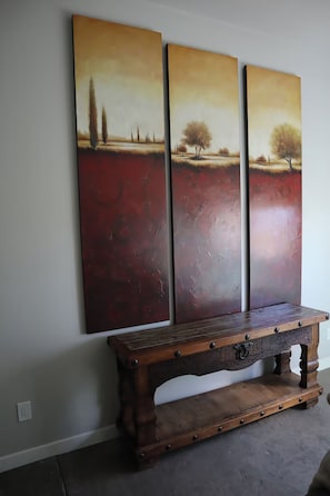 Eine Wand mit drei Bildern, die eine Landschaft, eine Holzbank und eine Steckdose zeigen.