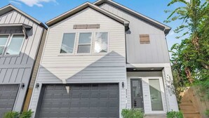 Ein zweistöckiges Wohnhaus mit Garage, Eingangstür und einer kleinen Veranda.