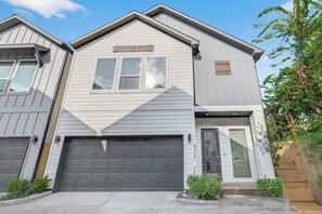 A two-story residential building with a garage, a front door, and a small porch area. - Houston 3BR Home w/ Parking - Near Top Attractions (Houston)