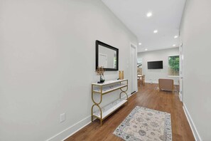 A hallway with a white wall, a gold console table, a mirror, and a patterned rug. - Houston 3BR Home w/ Parking - Near Top Attractions (Houston)