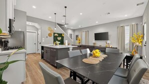 Una cocina moderna con comedor, una escalera y una sala de estar con televisor.