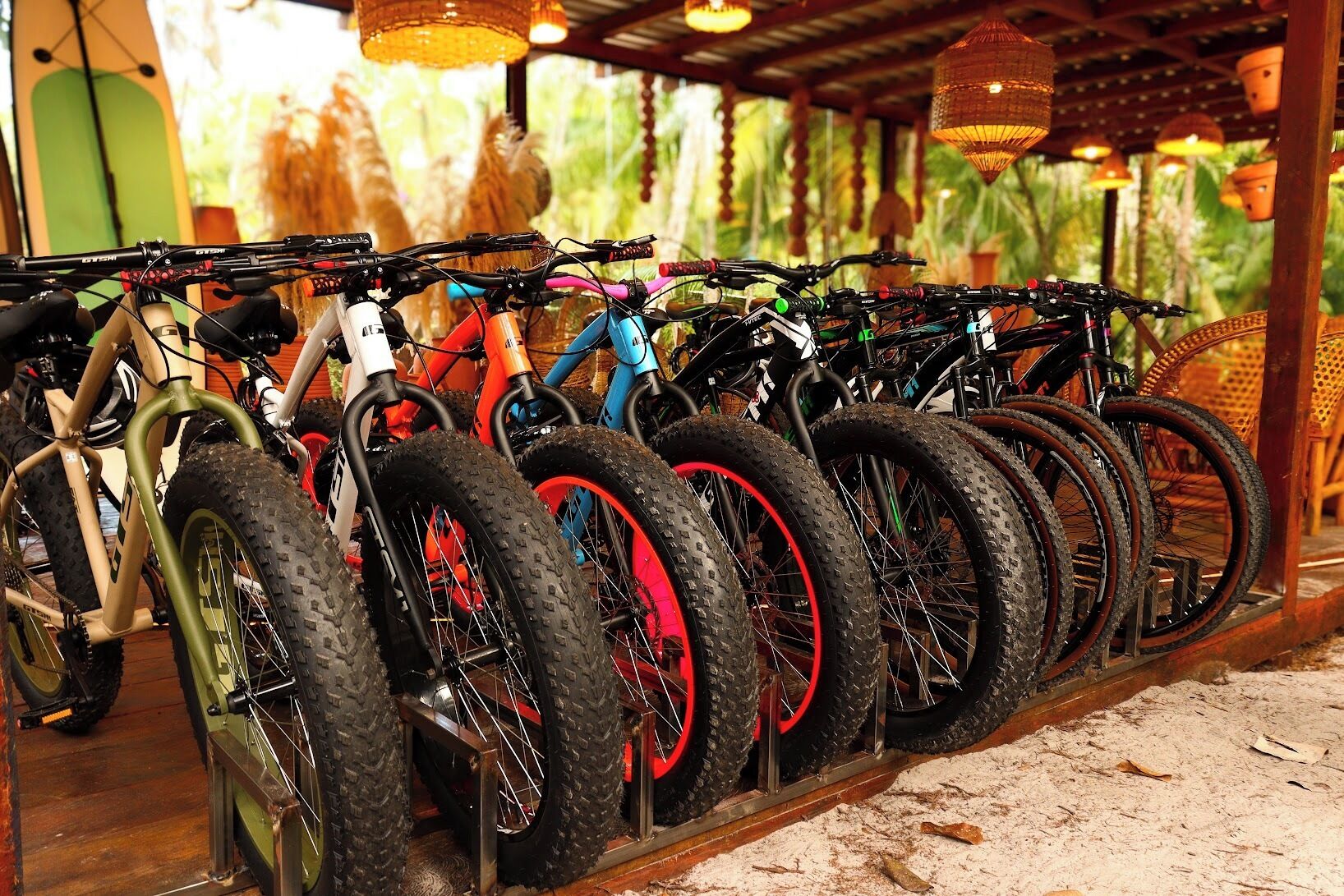 A row of bicycles parked in an outdoor area with a wooden structure overhead.