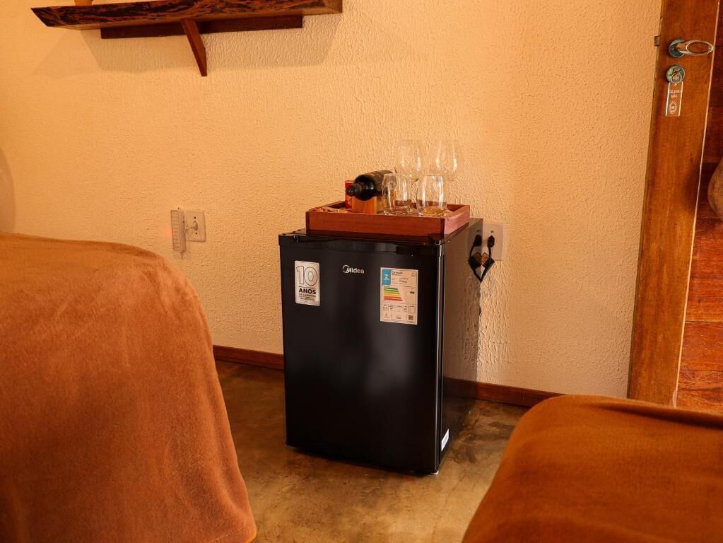 Una habitación compacta con minibar, un estante de madera y una puerta con manija.