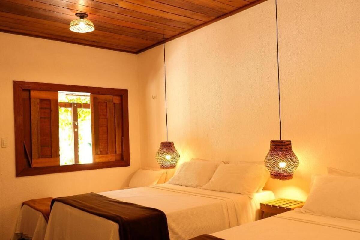 Habitación con dos camas, techo de madera y ventana con contraventanas.