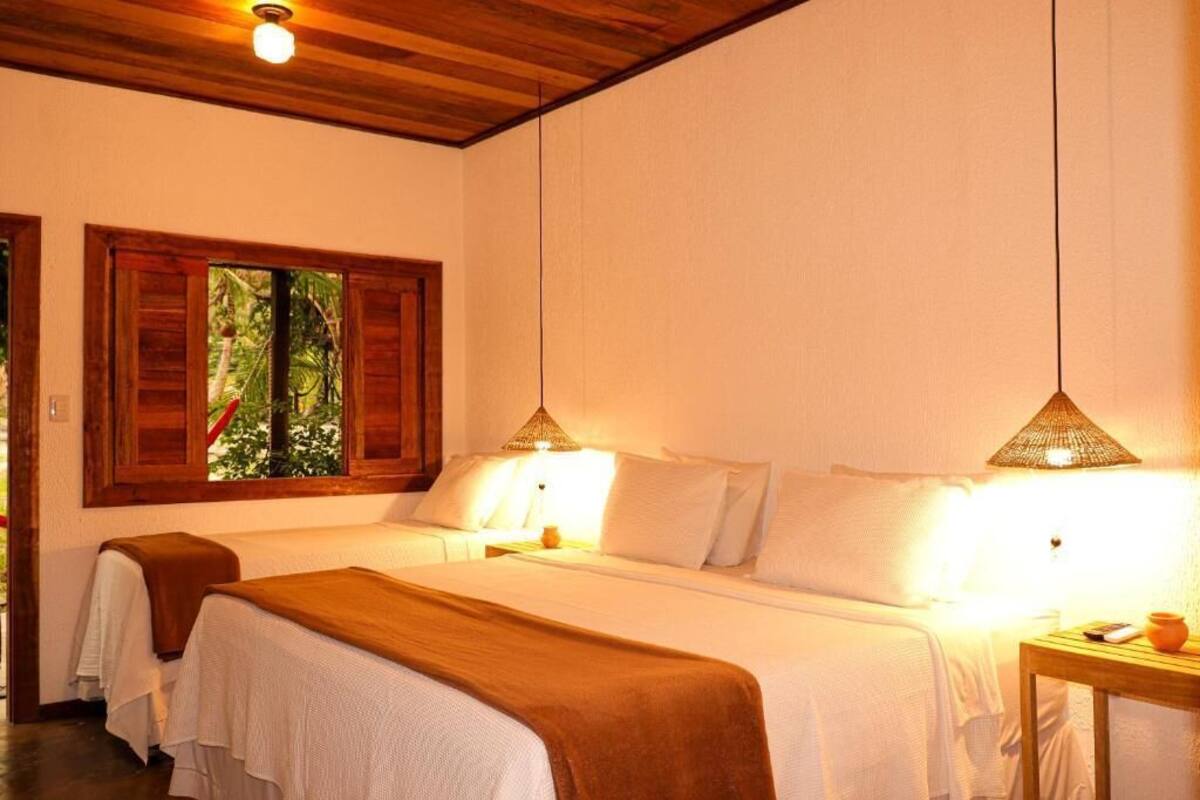 Habitación con dos camas, techo de madera y ventana con persianas.