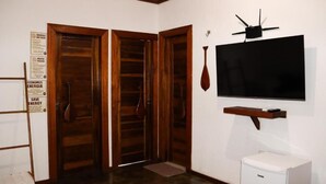 Huoneessa on puuovet, seinälle asennettu taulutelevisio ja lattialla pieni valkoinen laite.