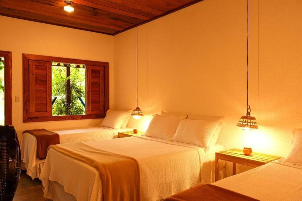 Una habitación con dos camas, cabeceros de madera y una ventana con contraventanas.
